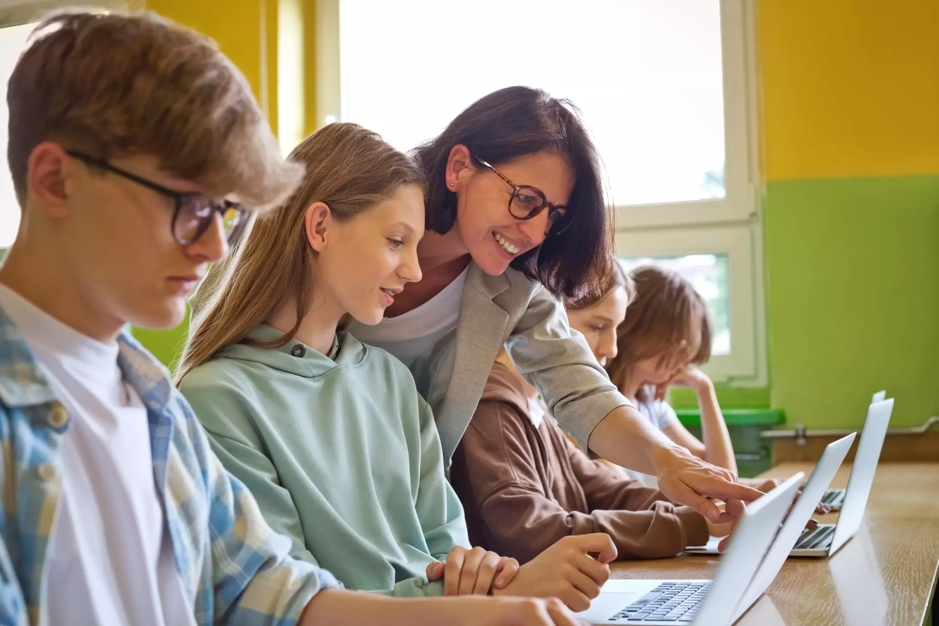 Un professeur et des enfants travaillant sur des ordinateurs.
