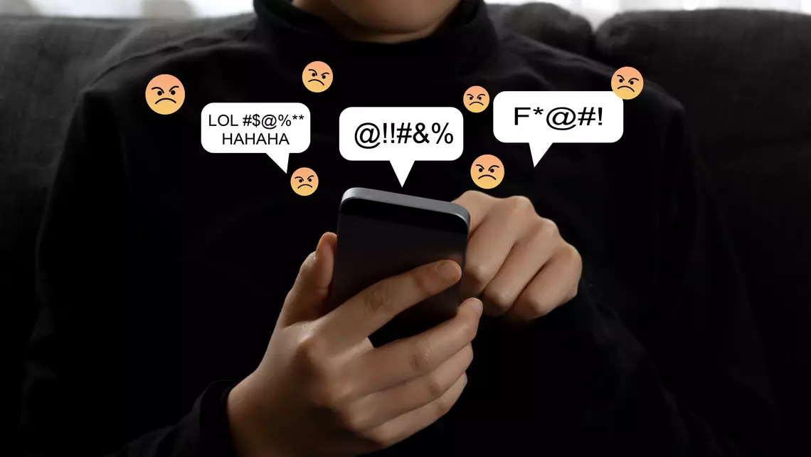 Un jeune tenant un smartphone d'où sortent des emojis négatives