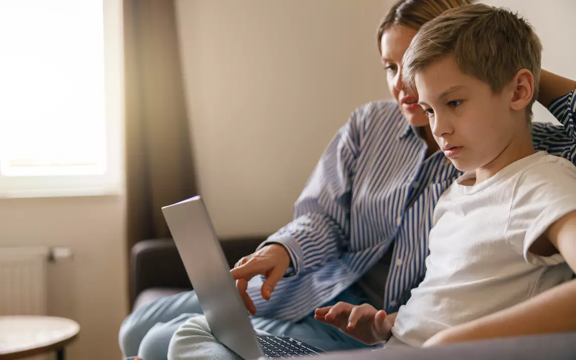 Parent et enfant regardant un écran d’ordinateur.